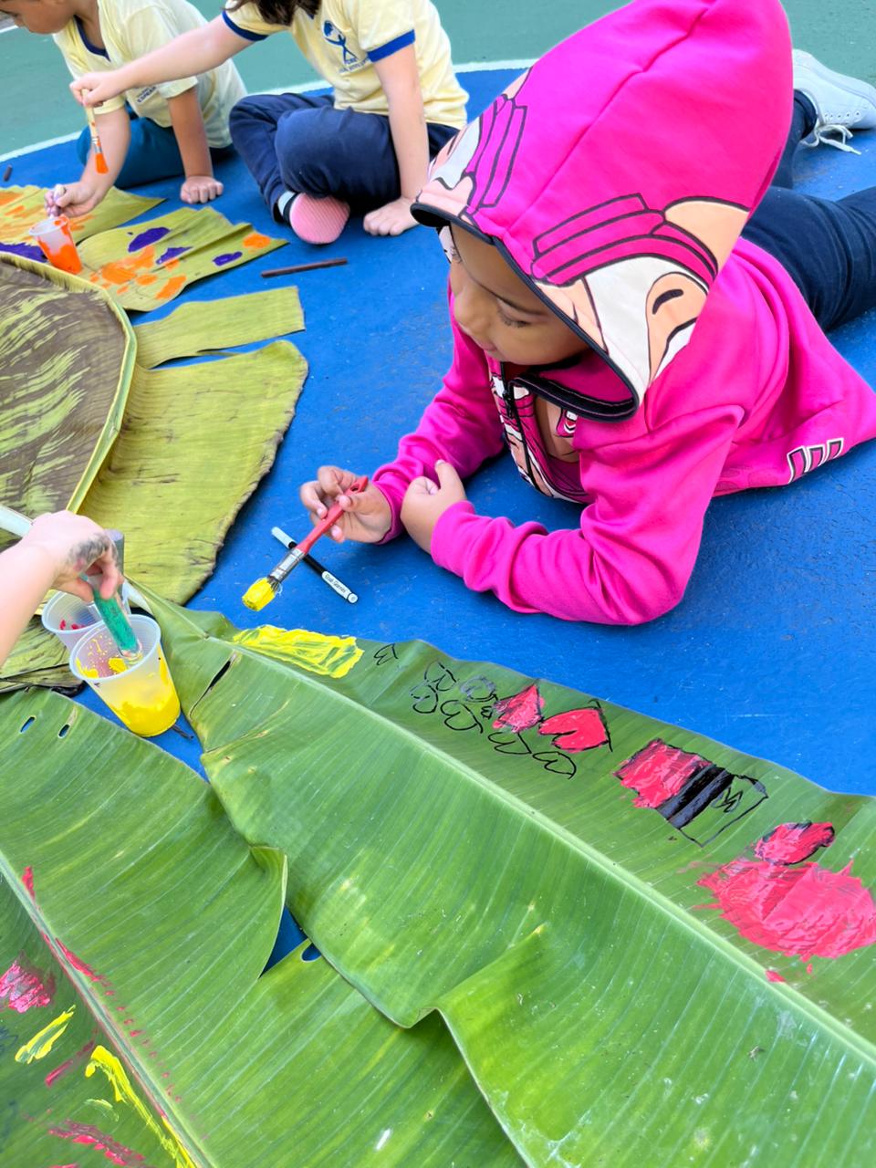 Criança pintando folhas com tinta